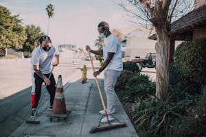Two volunteers engaged in a street cleaning effort, promoting social good and community service.